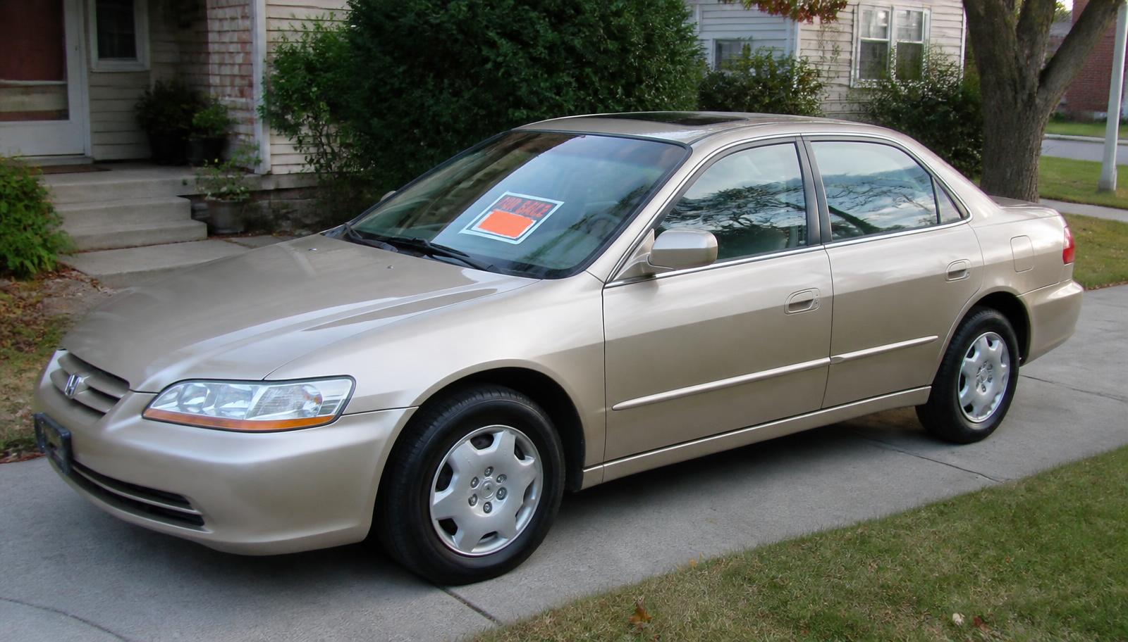 Clean, freshly detailed sedan parked in a driveway with a for-sale sign in the windshield